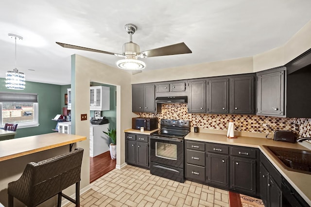 kitchen with tasteful backsplash, ceiling fan, sink, pendant lighting, and black electric range