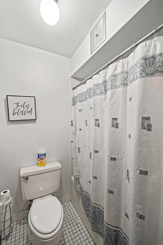 bathroom featuring tile patterned floors, shower / bath combo with shower curtain, and toilet