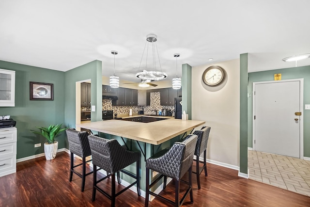 kitchen featuring a kitchen bar, pendant lighting, kitchen peninsula, and dark hardwood / wood-style floors