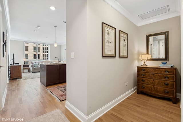 hall with crown molding, light hardwood / wood-style flooring, and sink