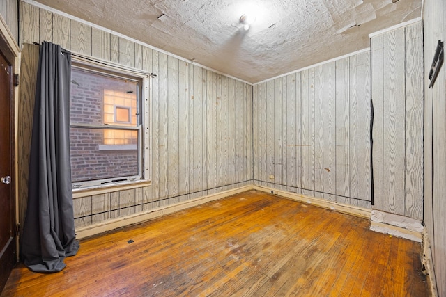 spare room with crown molding, wooden walls, and hardwood / wood-style flooring