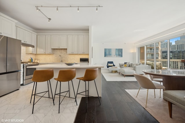 kitchen featuring a kitchen bar, appliances with stainless steel finishes, light wood-type flooring, and white cabinetry