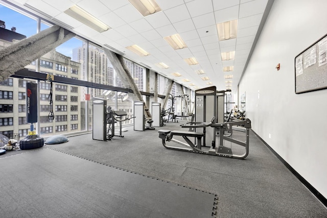 exercise room with a paneled ceiling and expansive windows