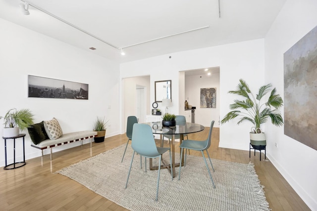 dining area featuring hardwood / wood-style floors and rail lighting