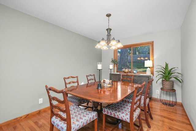 dining space with hardwood / wood-style flooring and a notable chandelier