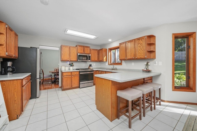 kitchen with a wealth of natural light, kitchen peninsula, sink, and appliances with stainless steel finishes