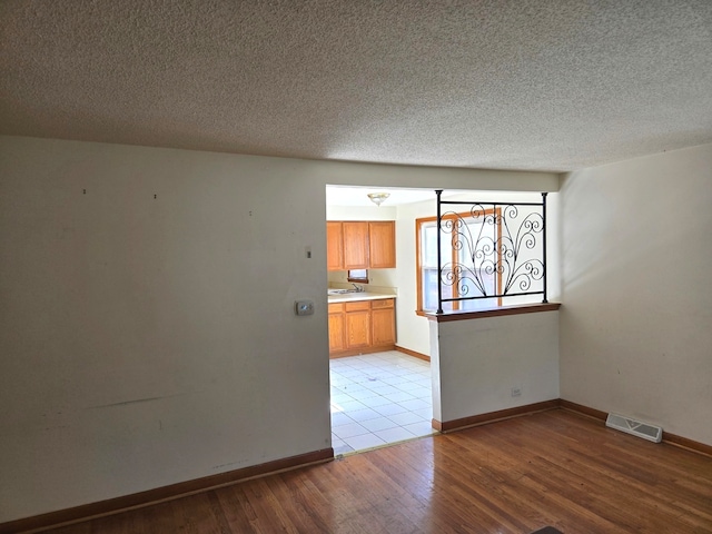 spare room with light hardwood / wood-style flooring, a textured ceiling, and sink