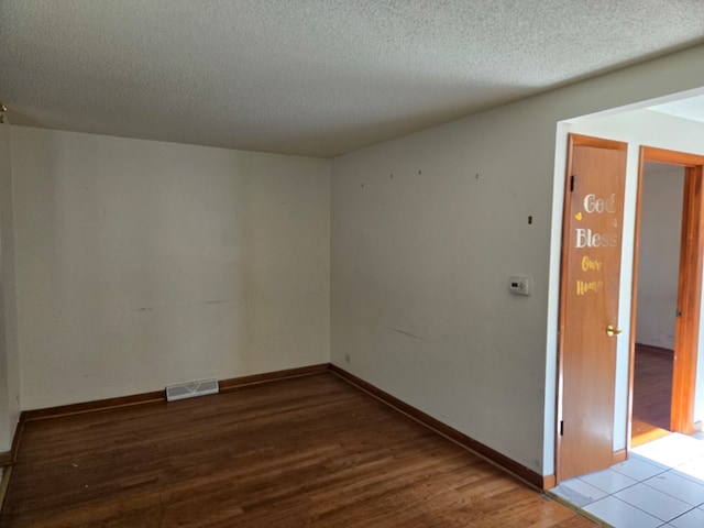 empty room featuring a textured ceiling and light hardwood / wood-style flooring