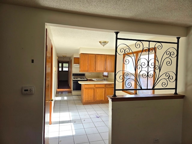 kitchen with white gas stove, light tile patterned flooring, a textured ceiling, and sink