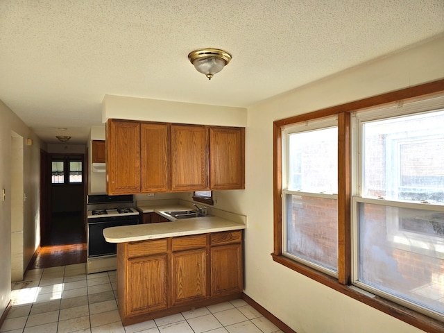 kitchen with kitchen peninsula, light tile patterned floors, a textured ceiling, and white range with gas cooktop