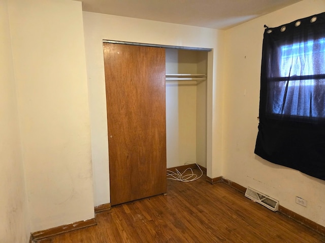 unfurnished bedroom with dark hardwood / wood-style flooring and a closet