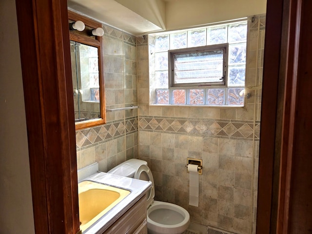 bathroom featuring vanity, toilet, and tile walls