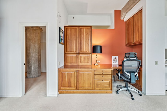 office area featuring light carpet, baseboards, and built in study area