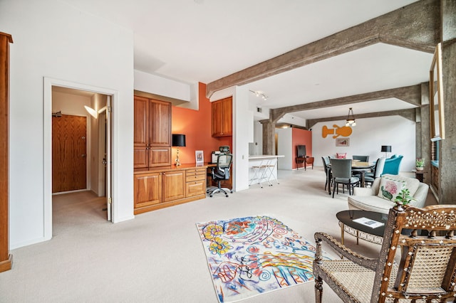 living room featuring beam ceiling, baseboards, built in desk, and light colored carpet