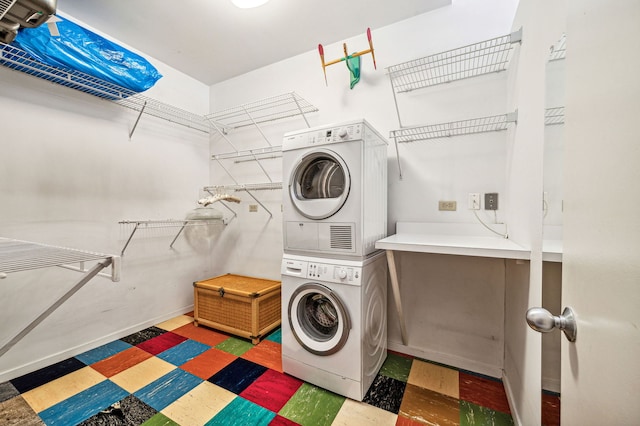 laundry room featuring stacked washer / drying machine, laundry area, baseboards, and tile patterned floors