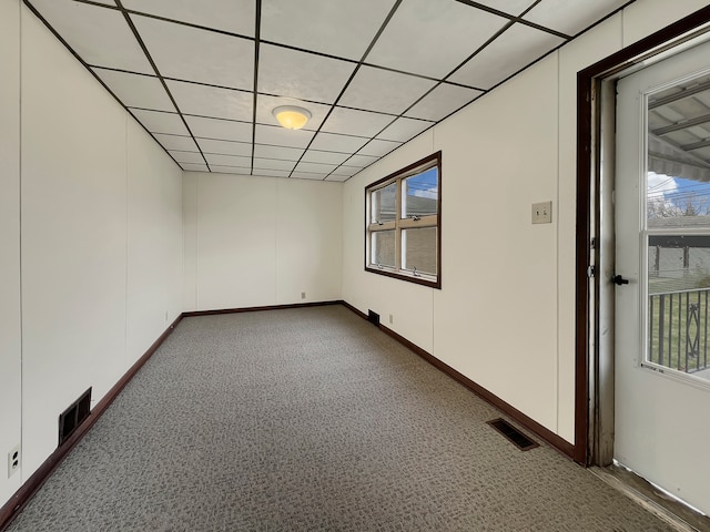 carpeted spare room with plenty of natural light and a drop ceiling