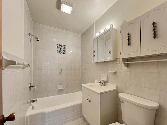 full bathroom featuring vanity, tiled shower / bath, tile patterned flooring, toilet, and tile walls