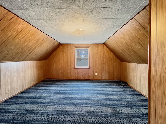 bonus room featuring wood walls, dark carpet, and lofted ceiling