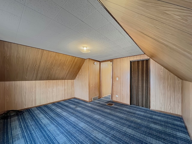 bonus room featuring wood walls, carpet, and vaulted ceiling