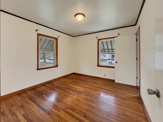 empty room with wood-type flooring and crown molding