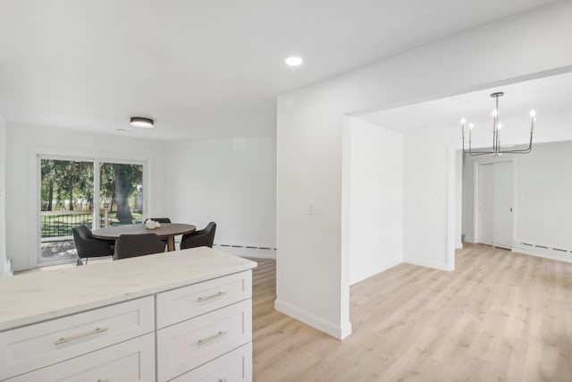 kitchen featuring a baseboard heating unit, white cabinets, light hardwood / wood-style flooring, light stone countertops, and decorative light fixtures