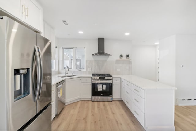 kitchen with white cabinetry, sink, wall chimney range hood, light hardwood / wood-style floors, and appliances with stainless steel finishes