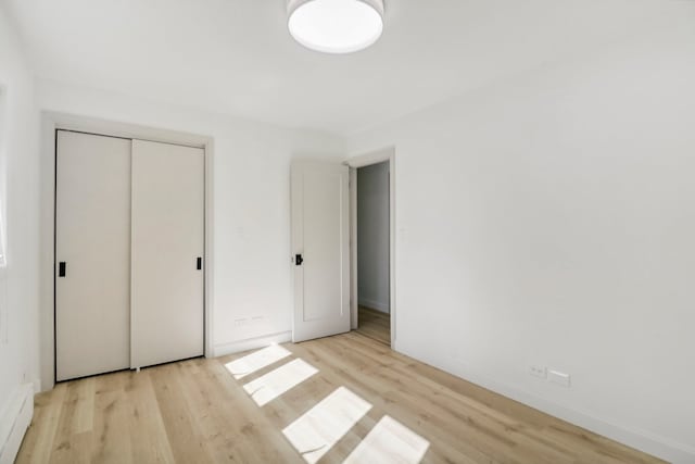 unfurnished bedroom with light wood-type flooring and a closet