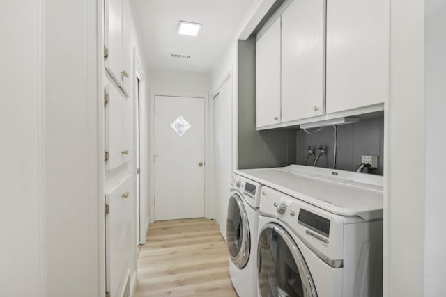 clothes washing area with cabinets, light hardwood / wood-style flooring, and washer and clothes dryer