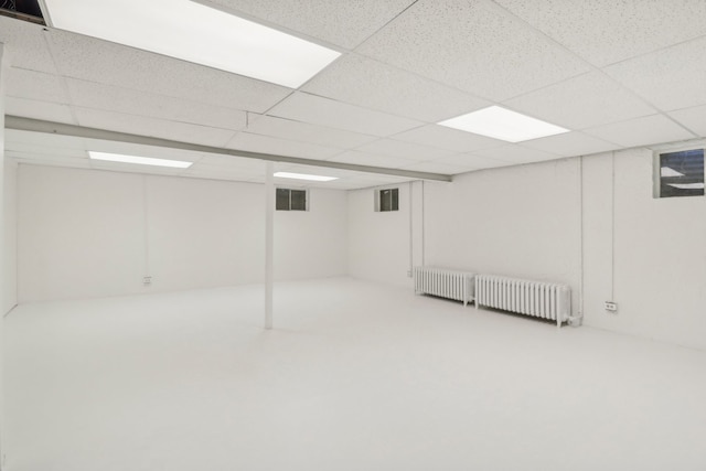 basement featuring a paneled ceiling and radiator