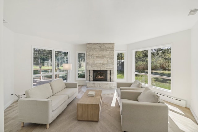 living room featuring light wood-type flooring, a fireplace, and a baseboard radiator