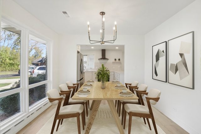 dining space featuring a baseboard heating unit, light wood-type flooring, and a chandelier