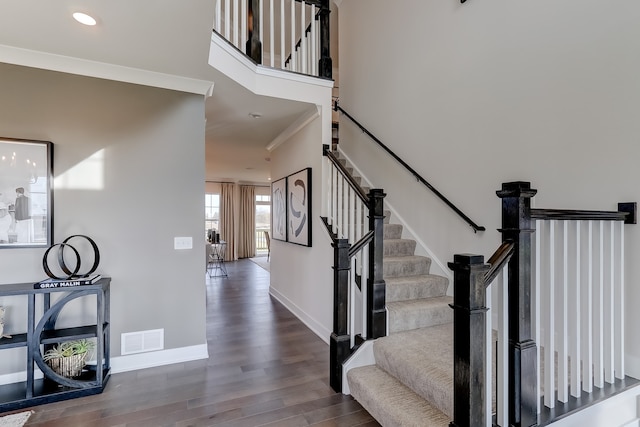 stairs with wood-type flooring and crown molding