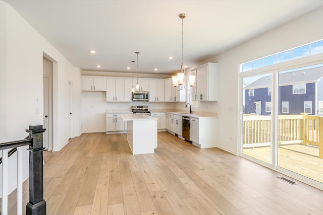 kitchen with light wood finished floors, visible vents, a kitchen island, appliances with stainless steel finishes, and light countertops