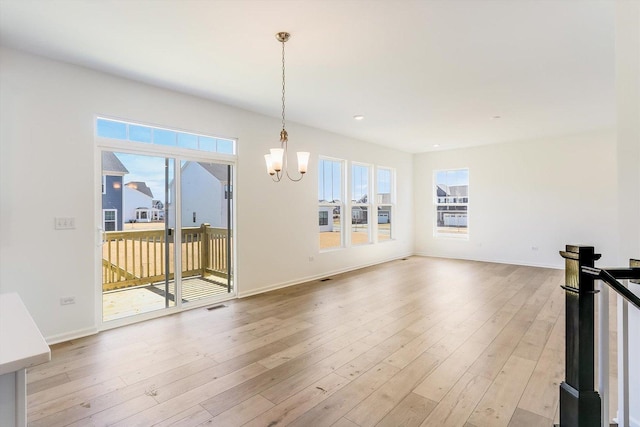 interior space featuring light wood-type flooring, baseboards, visible vents, and a notable chandelier