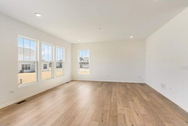 living room featuring a tile fireplace, a chandelier, a healthy amount of sunlight, and light hardwood / wood-style floors