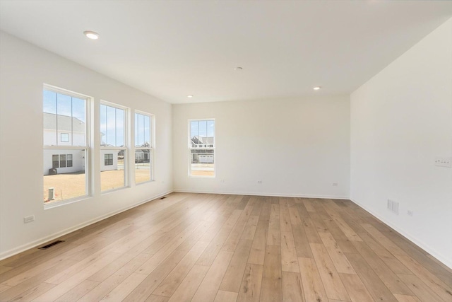 spare room featuring light wood-style floors, recessed lighting, visible vents, and baseboards