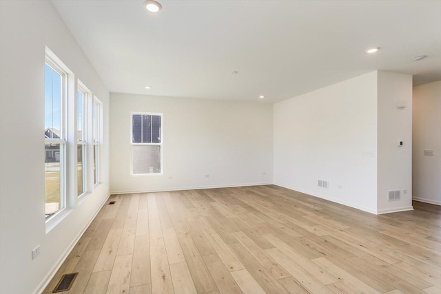 empty room with light wood-type flooring, a healthy amount of sunlight, visible vents, and recessed lighting