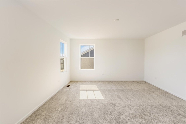 unfurnished room featuring baseboards, visible vents, and light colored carpet