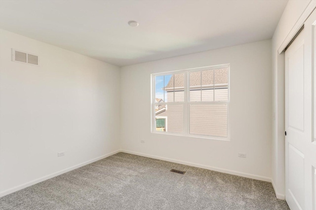 carpeted empty room with visible vents and baseboards