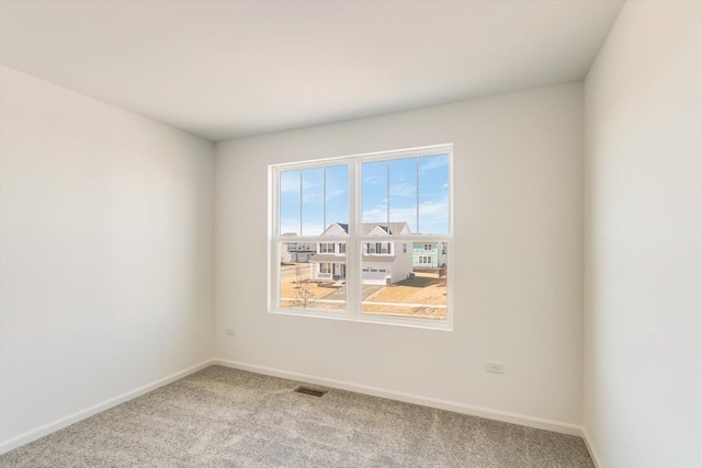 unfurnished room featuring carpet floors, visible vents, and baseboards