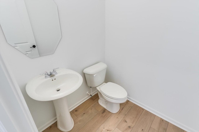 bathroom with baseboards, toilet, and wood finished floors