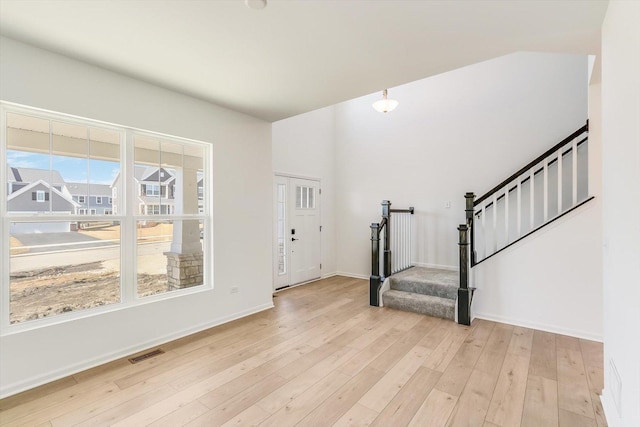 entrance foyer featuring light wood-style flooring, visible vents, stairway, and baseboards