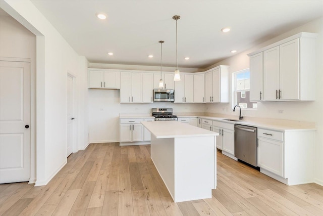 kitchen with stainless steel appliances, white cabinetry, a sink, and light wood-style flooring