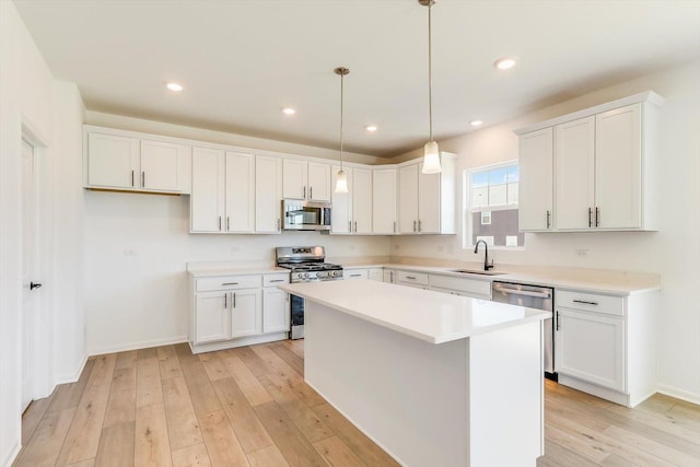 kitchen featuring a sink, white cabinetry, appliances with stainless steel finishes, a center island, and light wood finished floors