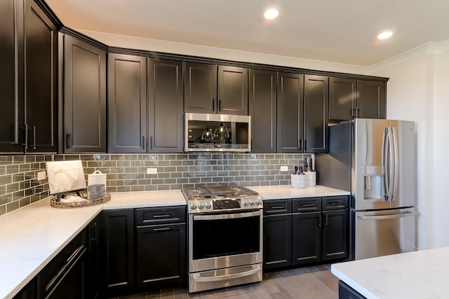 kitchen featuring appliances with stainless steel finishes, backsplash, crown molding, and hardwood / wood-style floors