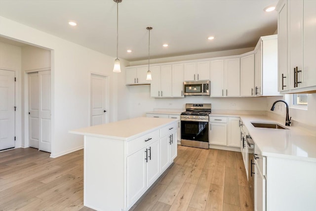 kitchen with light wood-style flooring, appliances with stainless steel finishes, light countertops, and a sink