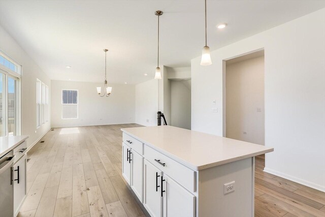 kitchen with stainless steel dishwasher, sink, light hardwood / wood-style flooring, a center island, and hanging light fixtures