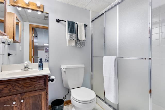 bathroom with vanity, a drop ceiling, toilet, and a shower with shower door