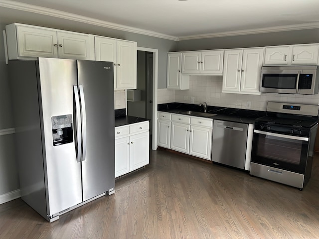 kitchen with appliances with stainless steel finishes, backsplash, dark wood-type flooring, sink, and white cabinetry