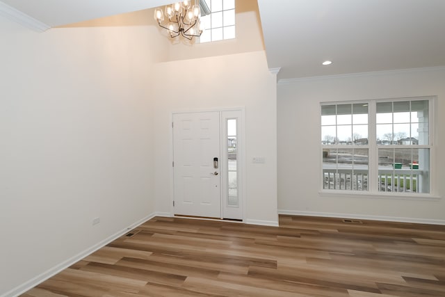 entryway with crown molding, an inviting chandelier, and hardwood / wood-style flooring